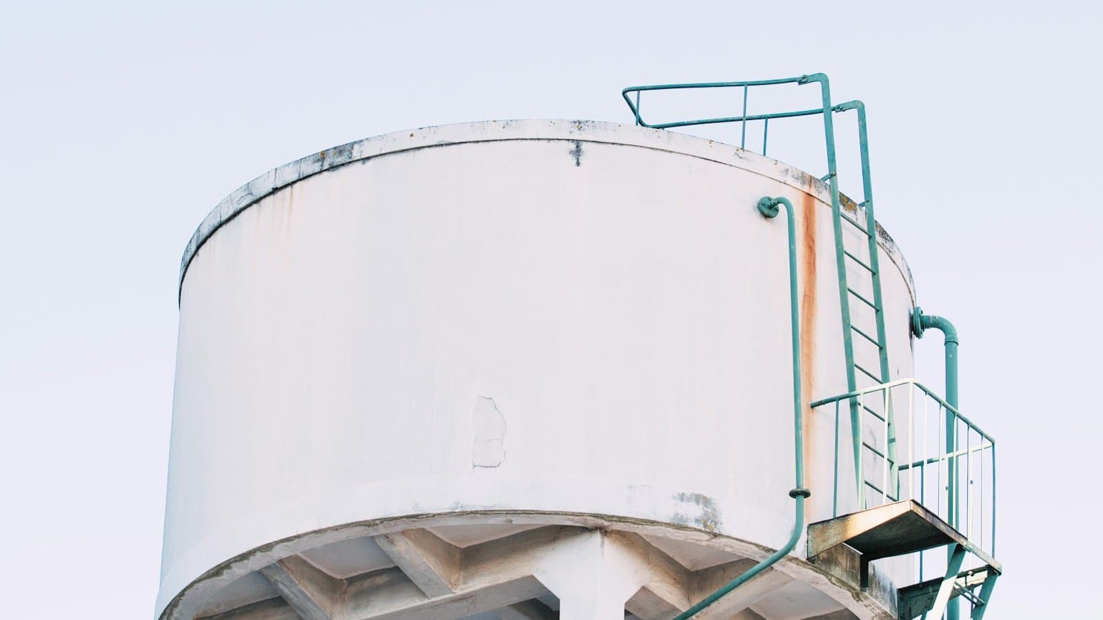 White welded steel water storage tank with external ladder and level piping